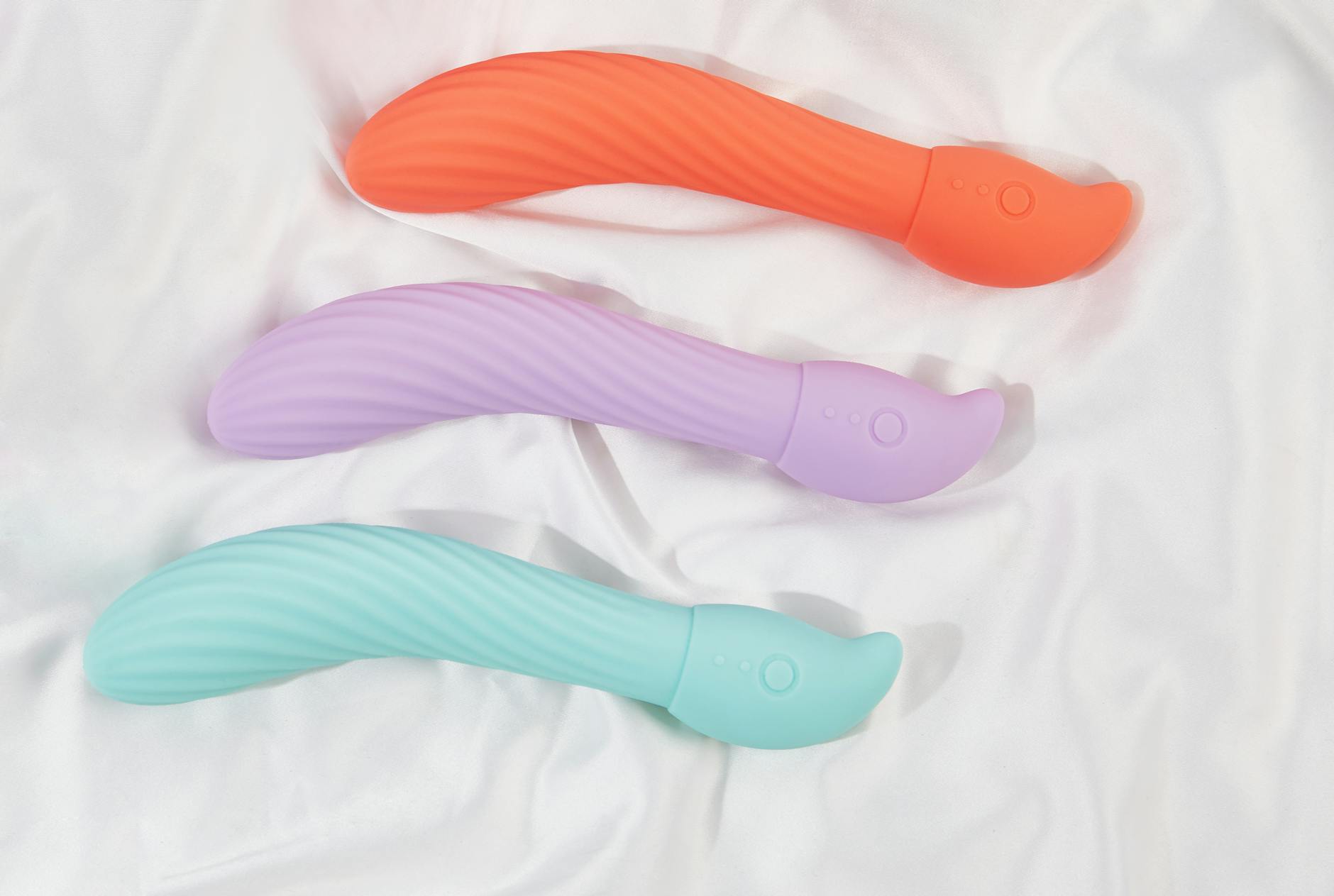 Three colorful lemon vibrators on white fabric, showing smooth textured surfaces designed for clitoral stimulation