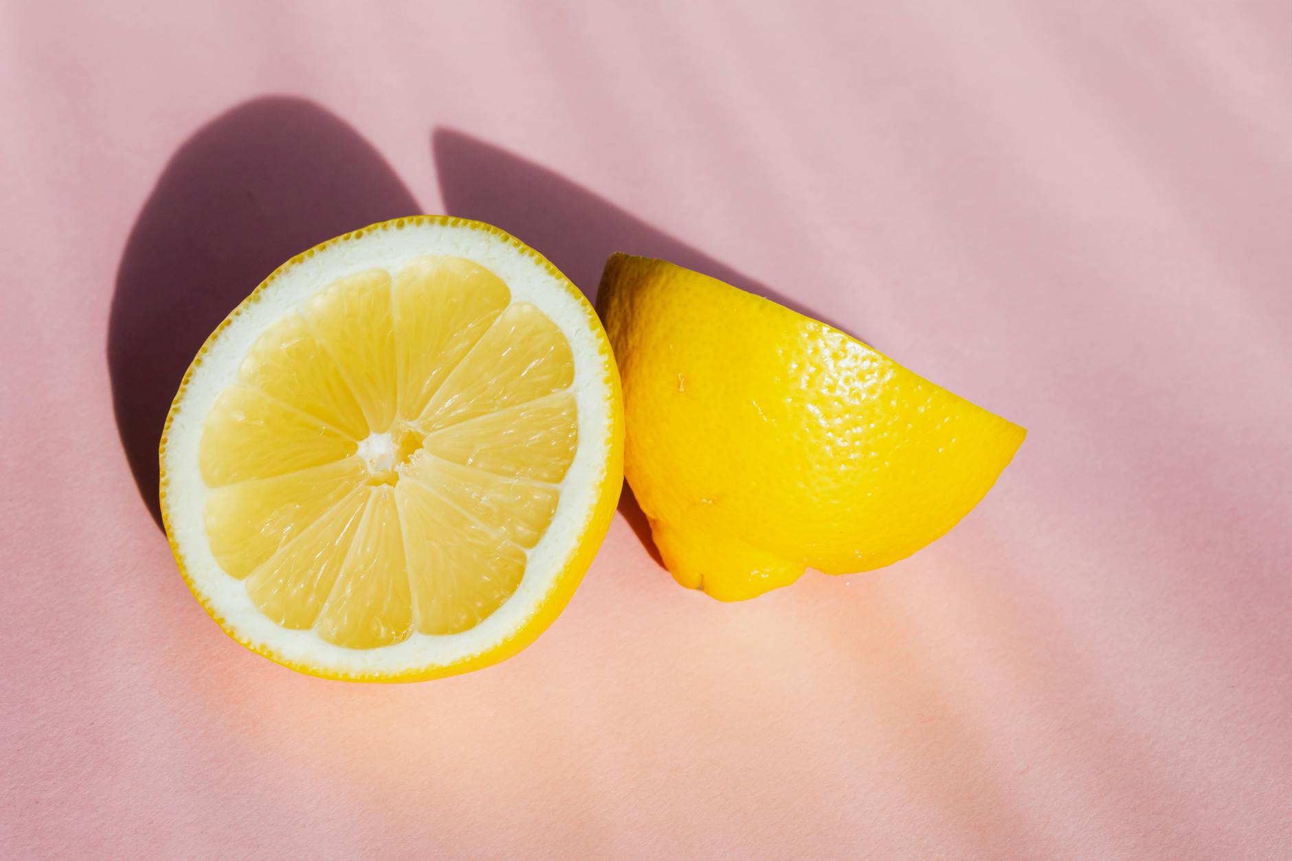Fresh halves of ripe lemon on a pink background, shot from above in natural sunlight