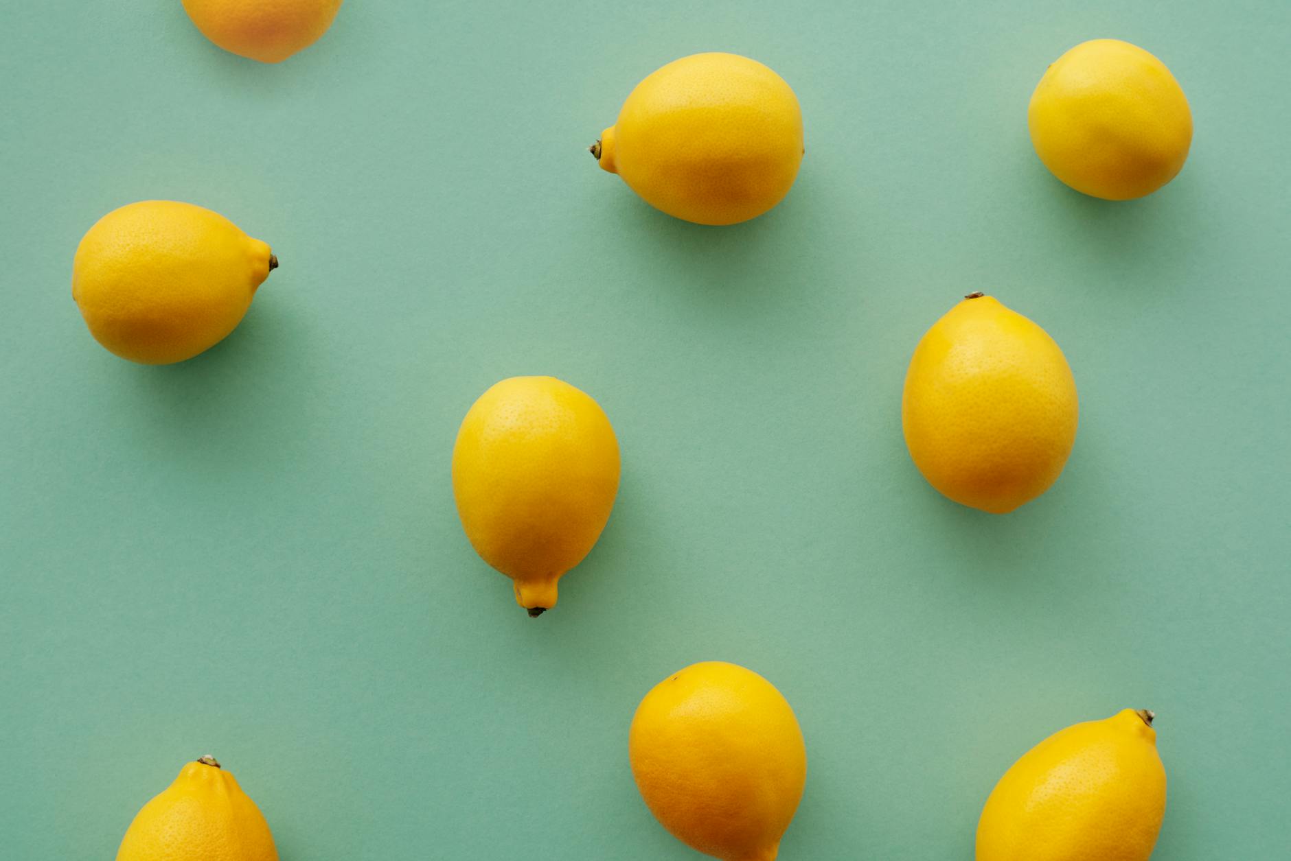Bright yellow lemons arranged on a pastel green background, representing fresh citrus energy and vitality