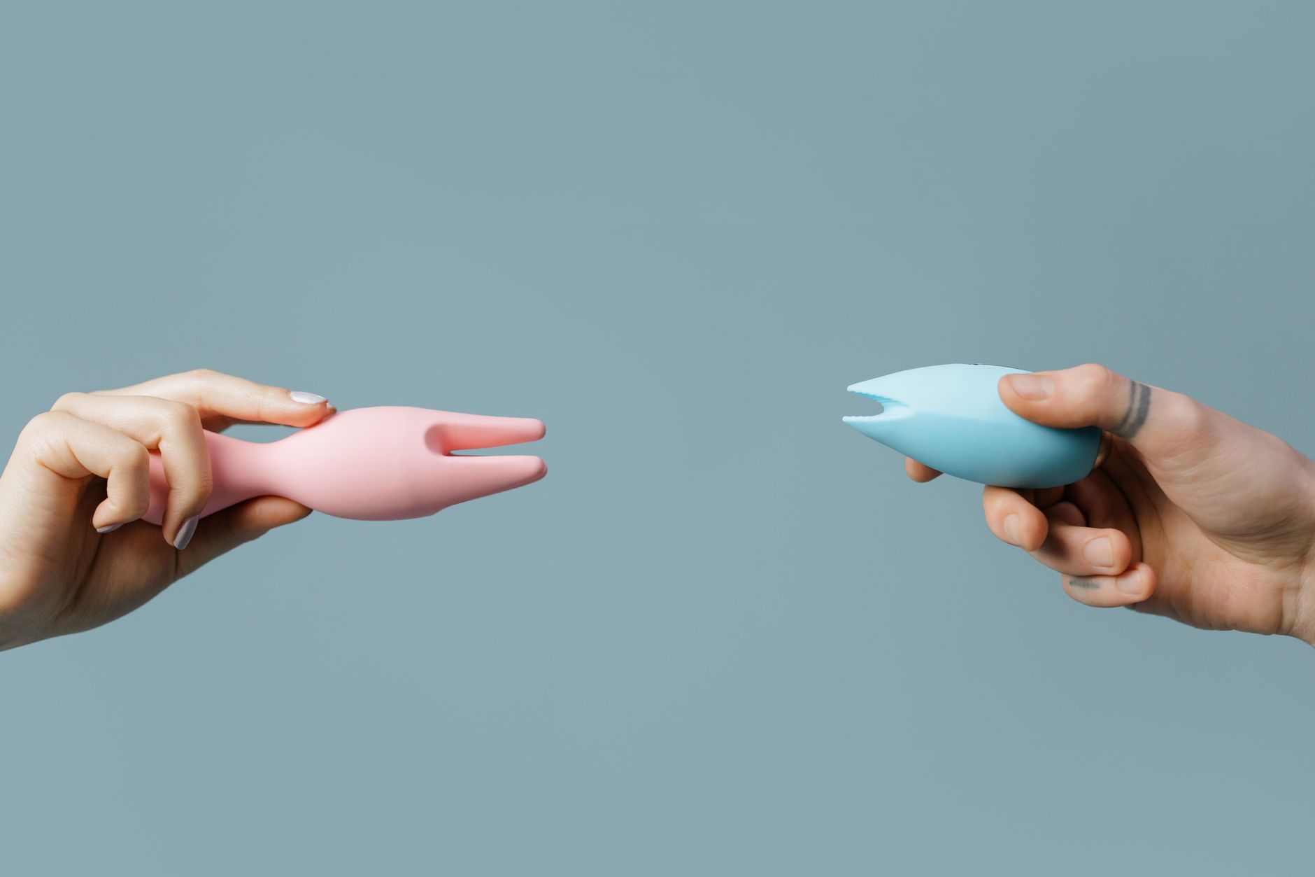 Hand holding a fresh lemon on a soft pink background, surrounded by additional lemons