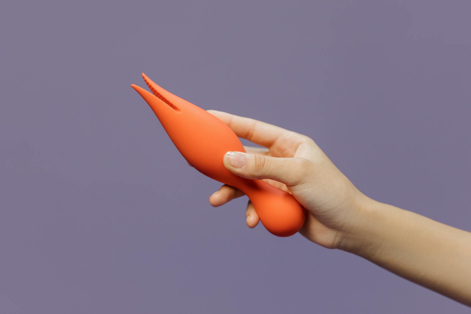 A hand holding a lemon-colored vibrator against a minimalist backdrop, representing gentle self-care for sensitive bodies